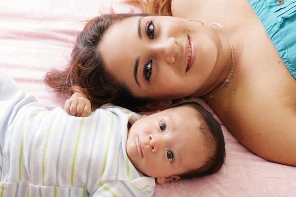 Portrait of happy young attractive hispanic mother lying with he - Photo, Image