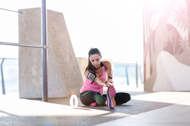 Νεαρή γυναίκα κάνει τέντωμα άσκηση στην αστική περιοχή - Φωτογραφία, εικόνα