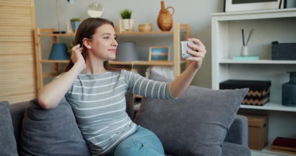 Slow motion of pretty woman taking selfie with smartphone touching hair at home - Filmagem, Vídeo