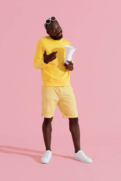 Black man in fashion clothes with megaphone on pink background - Zdjęcie, obraz