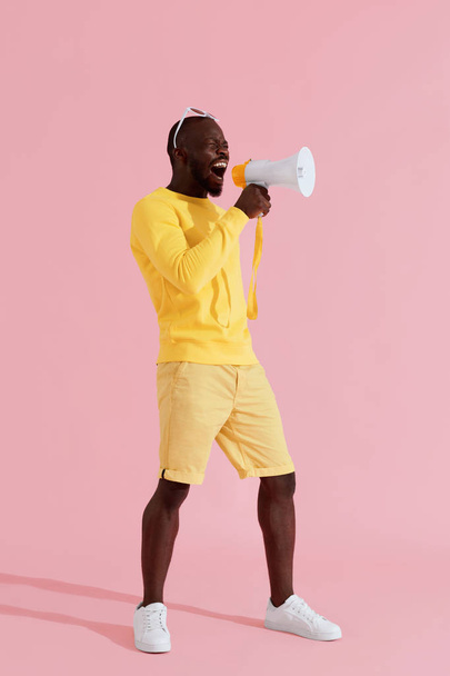 Attention! Black man shouting in megaphone on pink background - Fotó, kép