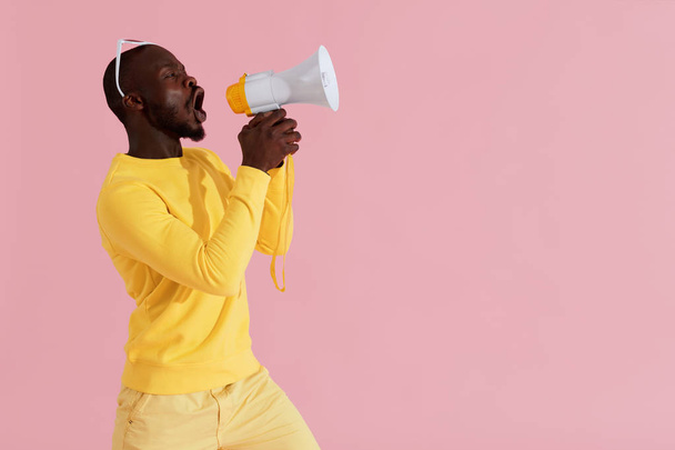 Black man shouting in megaphone on pink background portrait - Fotó, kép