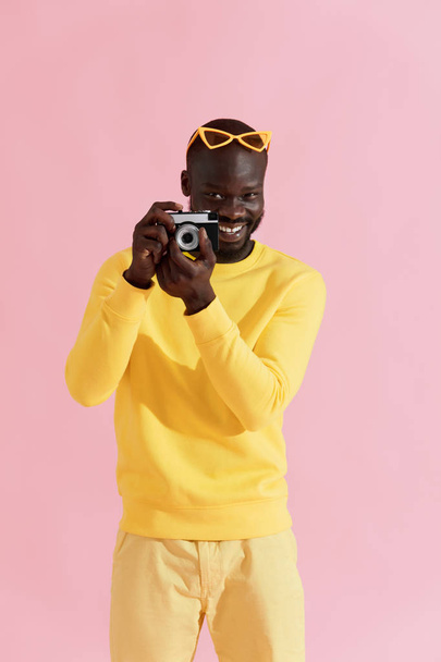 Happy man photographer with photo camera on colorful background - Fotó, kép