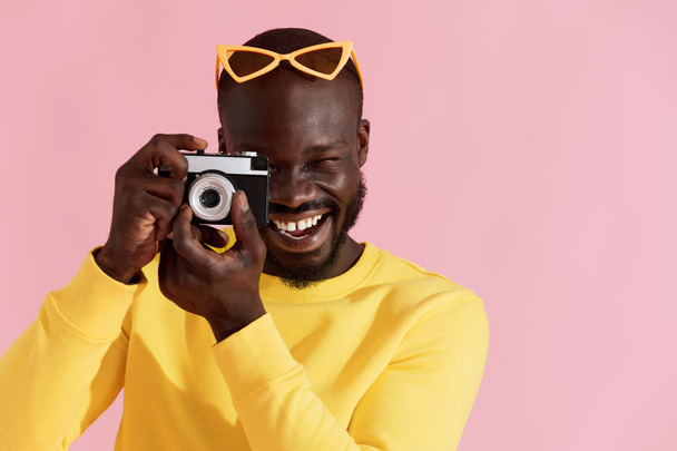 Happy man photographer with photo camera on colorful background - Fotó, kép