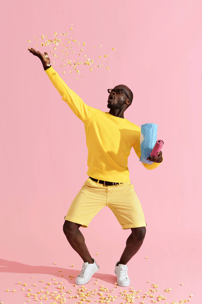 Happy man in cinema glasses having fun throwing pop corn in air - Foto, afbeelding
