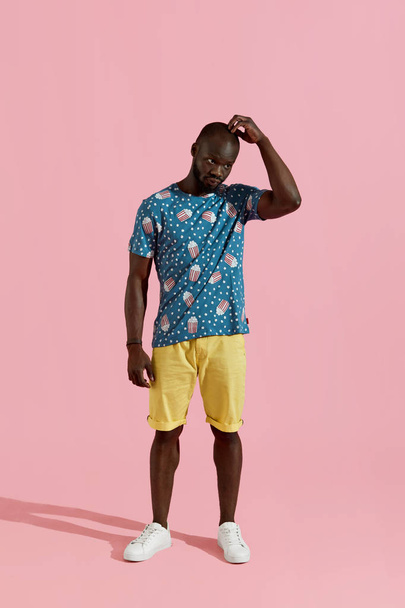 Fashion. Black man in stylish clothes on pink background  - Фото, изображение