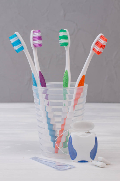 Οδοντόβουρτσα σε γυαλί, οδοντικό νήμα και τσίχλες. - Φωτογραφία, εικόνα
