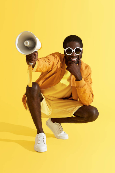 Fashion. Smiling black man in stylish clothes with megaphone - Foto, afbeelding