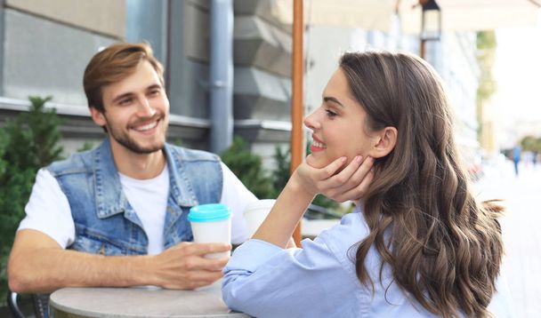 Piękna Młoda para rozmawia ze sobą i uśmiechnięta, delektując się kawą w kawiarni razem. - Zdjęcie, obraz