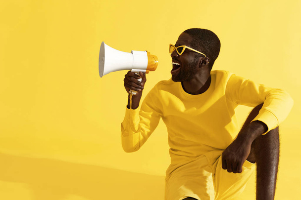 Man screaming in megaphone on yellow background portrait - Foto, Imagem