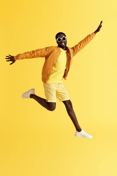 Jump. Happy man jumping in air and laughing on yellow background - Foto, Imagem