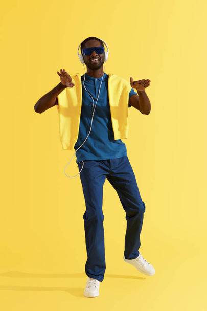 音楽を聴くヘッドフォンの男、黄色の背景で踊る - 写真・画像