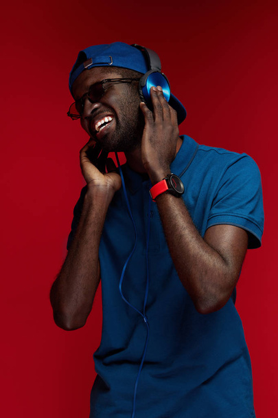 Black man in headphones listening music and singing portrait - Fotó, kép
