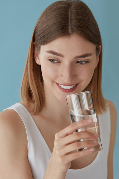 Femme souriante avec verre d'eau portrait intérieur
 - Photo, image
