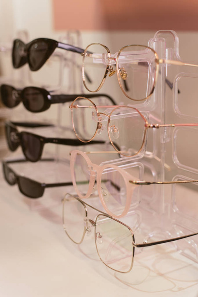 Stojak ze stylowymi, modnymi plastikowymi okularami. Sprzedaż detaliczna stylowych okularów - Zdjęcie, obraz