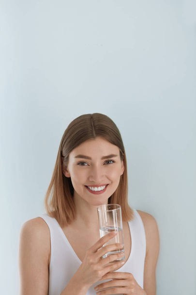 Woman with glass of fresh water in white portrait - 写真・画像