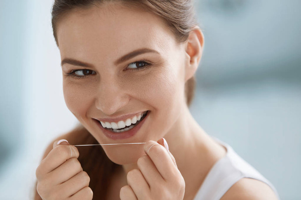Dental floss. Smiling woman cleaning white teeth with floss - Φωτογραφία, εικόνα