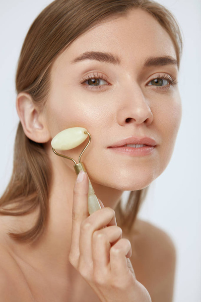 Gesichtsmassage. Frau benutzt Jade-Walze für Schönheitsbehandlung - Foto, Bild