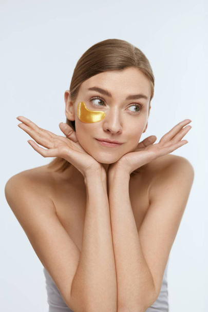 Eye patch. Woman with gold under eye pads on beauty face - Fotó, kép