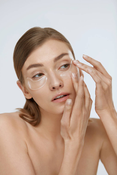 Eye skin care. Woman applying beauty patch mask under eyes - Foto, Bild