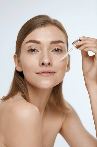 Skin care. Woman applying serum or facial oil on beauty face - Fotografie, Obrázek