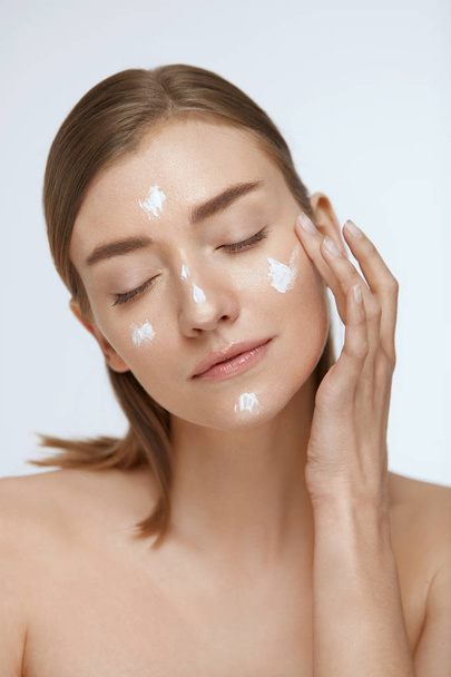 Skin care. Woman applying facial cream on beauty face closeup - Фото, изображение