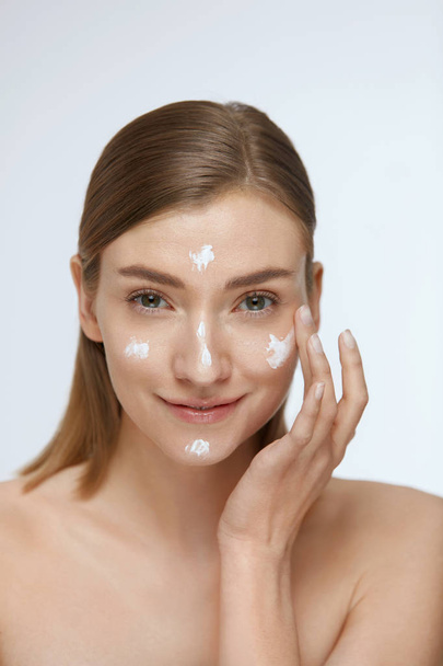 Skin care. Woman applying facial cream on beauty face closeup - 写真・画像