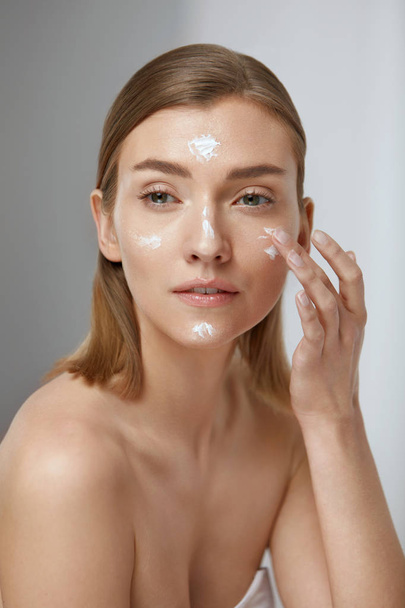 Skin care. Woman applying facial cream on beauty face closeup - Фото, зображення