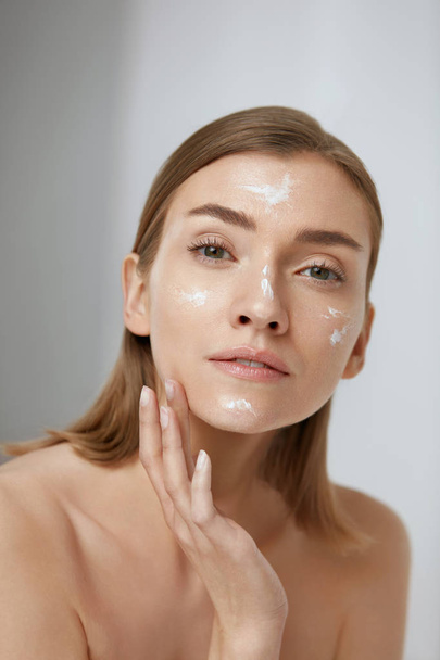 Skin care. Woman applying facial cream on beauty face closeup - Zdjęcie, obraz