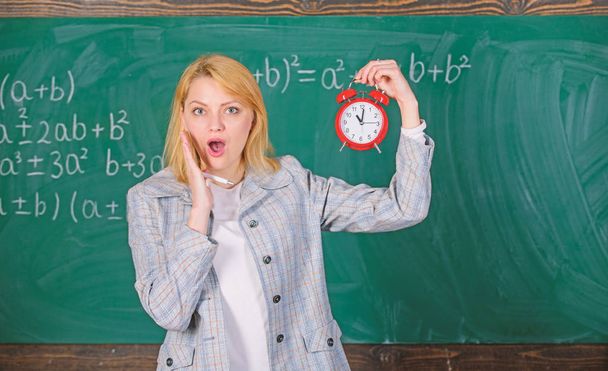 Experienced educator start lesson. She cares about discipline. What time is it. Woman teacher hold alarm clock. Girl formal wear school lecturer. Time to study. Welcome teacher school year - Фото, изображение