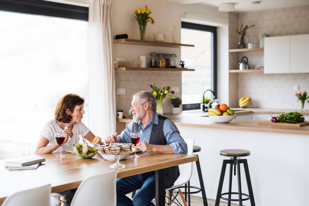 Senior couple in love having lunch indoors at home, talking. - Фото, зображення