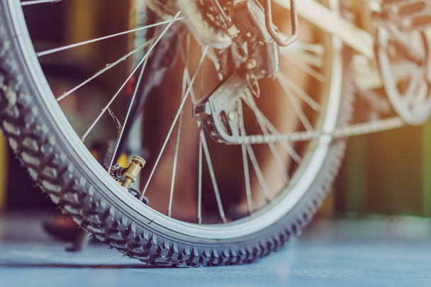 Крупным планом молодой человек готовится накачать старое велосипедное колесо в своем доме. . - Фото, изображение