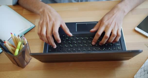Close-up of mans hands using laptop computer at desk in office typing - Materiał filmowy, wideo