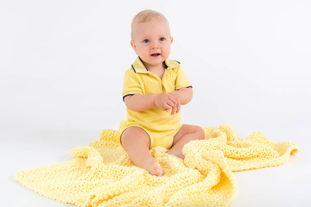 Το παιδί στην βελούδινη κίτρινη κουβέρτα στο λευκό φόντο - Φωτογραφία, εικόνα
