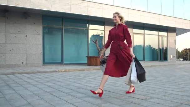 Chica joven caminar cerca de un centro comercial con lleno de compras bolsas de compras
 - Metraje, vídeo