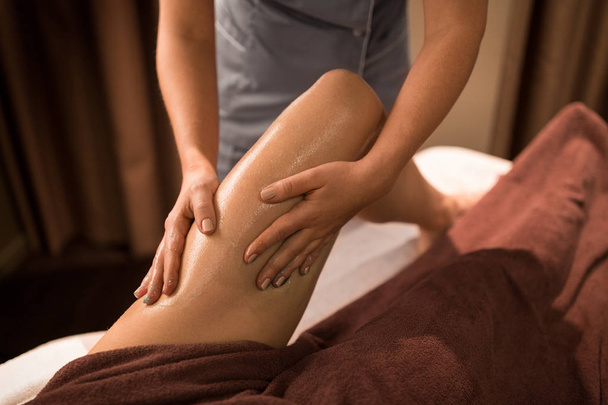 woman lying and having leg massage with gel at spa - Zdjęcie, obraz