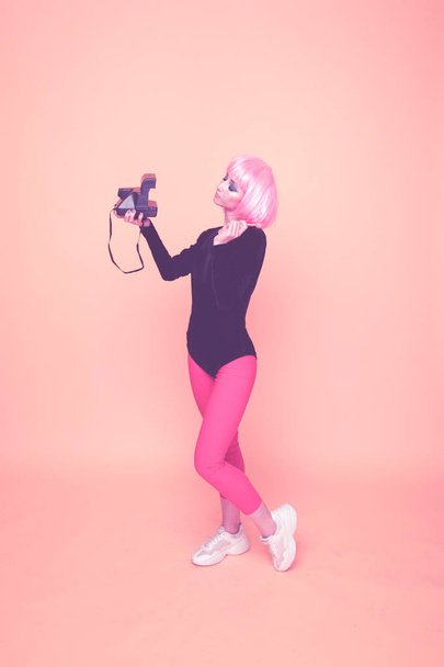 90s fashion concept. Girl in a pink wig holding camera. - Photo, Image