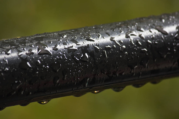 Barre de main courante noire humide recouverte de gouttelettes d'eau de pluie
 - Photo, image