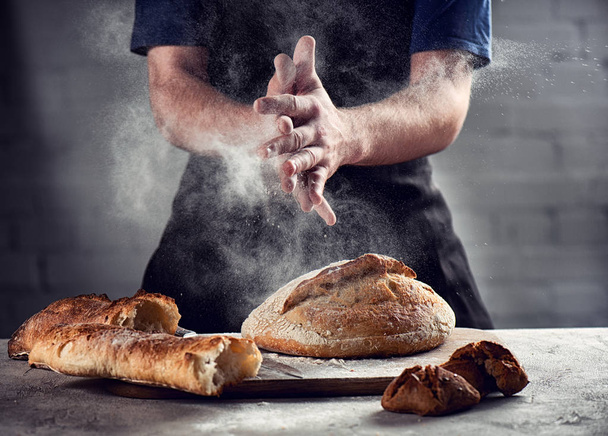 Chef espolvorea pan fresco con harina en la cocina
 - Foto, Imagen