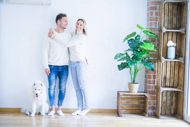 Jovem casal bonito com cão de pé na nova casa
 - Foto, Imagem