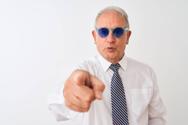 Старший седой бизнесмен в галстуке и солнцезащитных очках на изолированном белом фоне, указывая пальцем на камеру и на вас, знак руки, позитивный и уверенный жест спереди
 - Фото, изображение
