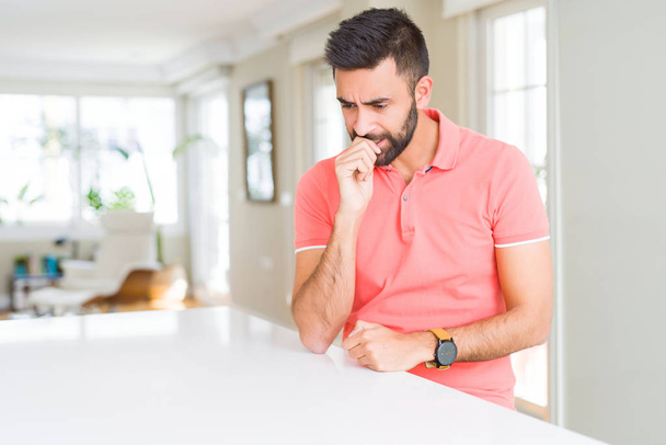 Handsome hispanic man wearing casual t-shirt at home looking stressed and nervous with hands on mouth biting nails. Anxiety problem. - Photo, Image
