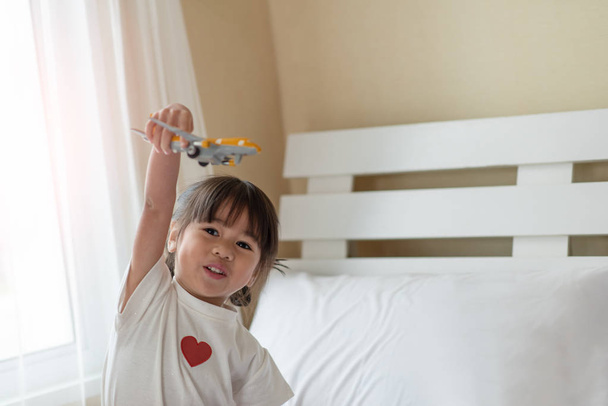 Gelukkig Aziatisch kind geniet van het spelen met speelgoed vliegtuig in handen - Foto, afbeelding