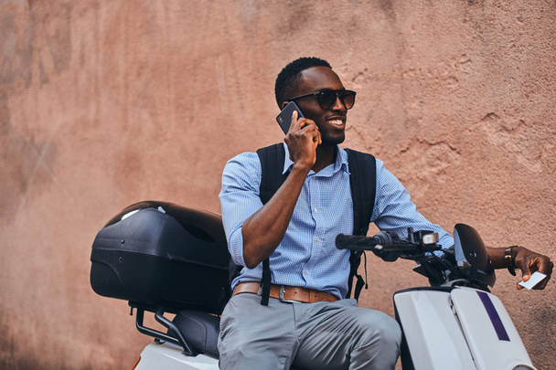 Fiatal fekete férfi robogó mobiltelefonnal - Fotó, kép