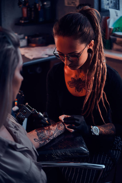 Maestro e cliente del tatuaggio alla sessione del tatuaggio
 - Foto, immagini