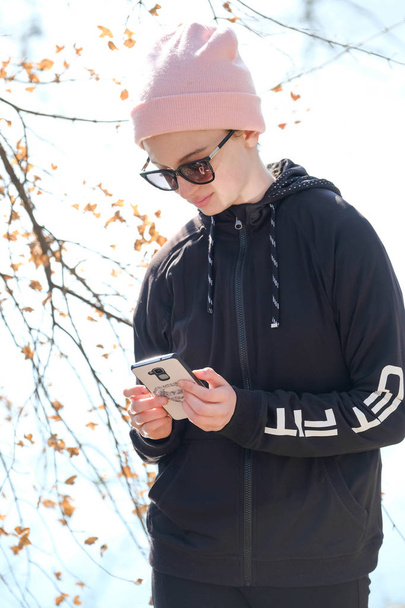  uśmiechnięta nastolatka w różowym kapeluszu i okularach przeciwsłonecznych słuchać muzyki - Zdjęcie, obraz
