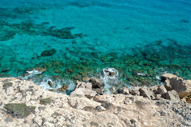 Ocean rocks aerial top view amazing nature background. Azure beach with rocky mountains and clear water of Cyprus  - Photo, Image