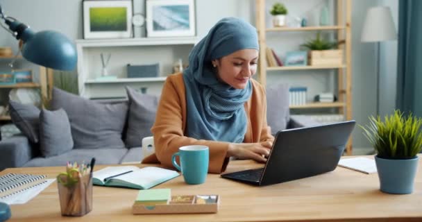 Independent girl in hijab freelancer working with laptop in apartment - Filmagem, Vídeo