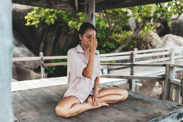 Young woman meditating in a yoga pose at the beach - Photo, image