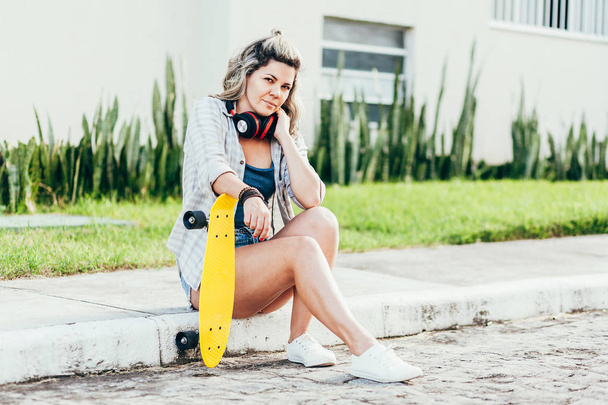 Portrait of beautiful woman with skateboard in the city. - Foto, afbeelding